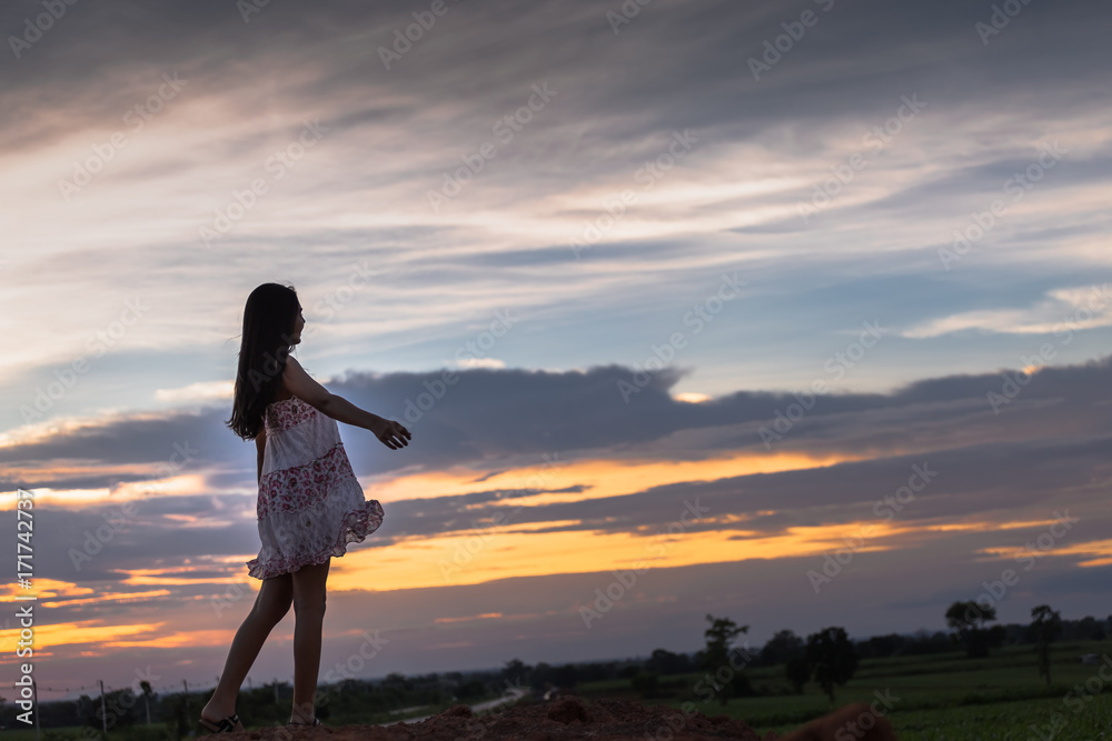Beautiful asian woman standing on the .mound with sunset