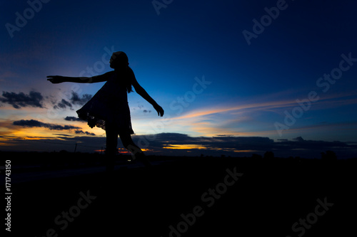 Silhouette of woman posing at sunset or sunrise © DarKinG