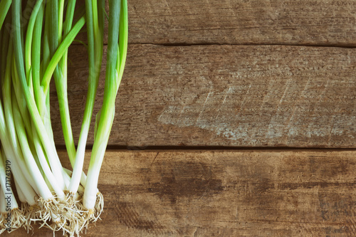 Fresh spring onion on wood table. Close up scallions or spring onion on wood plank in top view flat lay with copy space. Prepare spring onion for cooking. Food and vegetable concept for background. photo