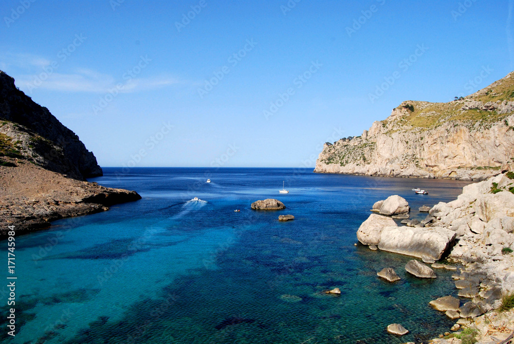 High View over stunning blue mediterranean sea and cliffs, secluded cove with boats in the distance