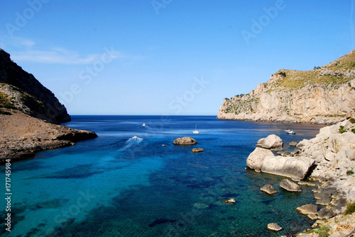 High View over stunning blue mediterranean sea and cliffs, secluded cove with boats in the distance