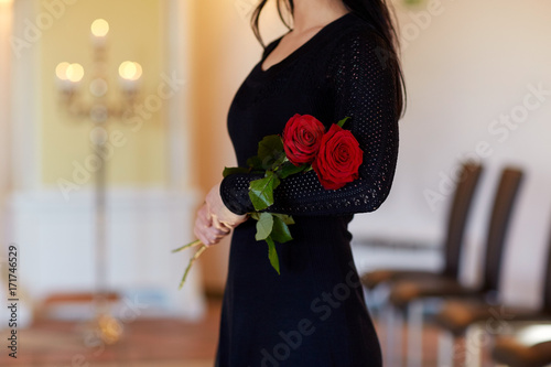 woman with red roses at funeral in church