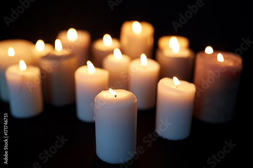 candles burning in darkness over black background
