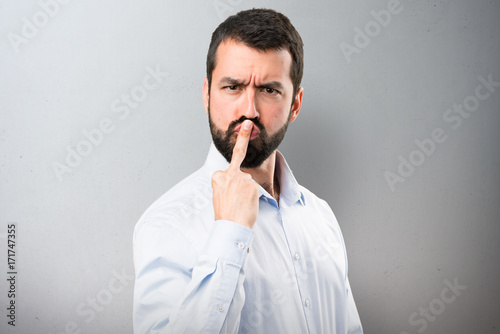 Handsome man with beard making horn gesture on textured background