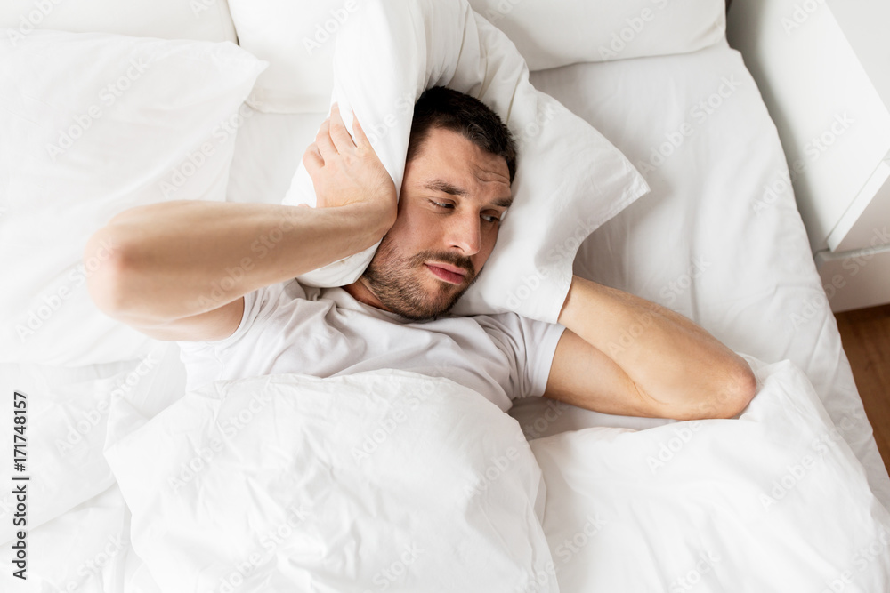 man in bed with pillow suffering from noise man in bed with pillow suffering from noise