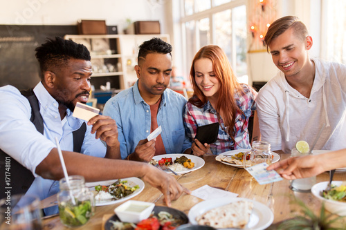 happy friends with money paying bill at restaurant