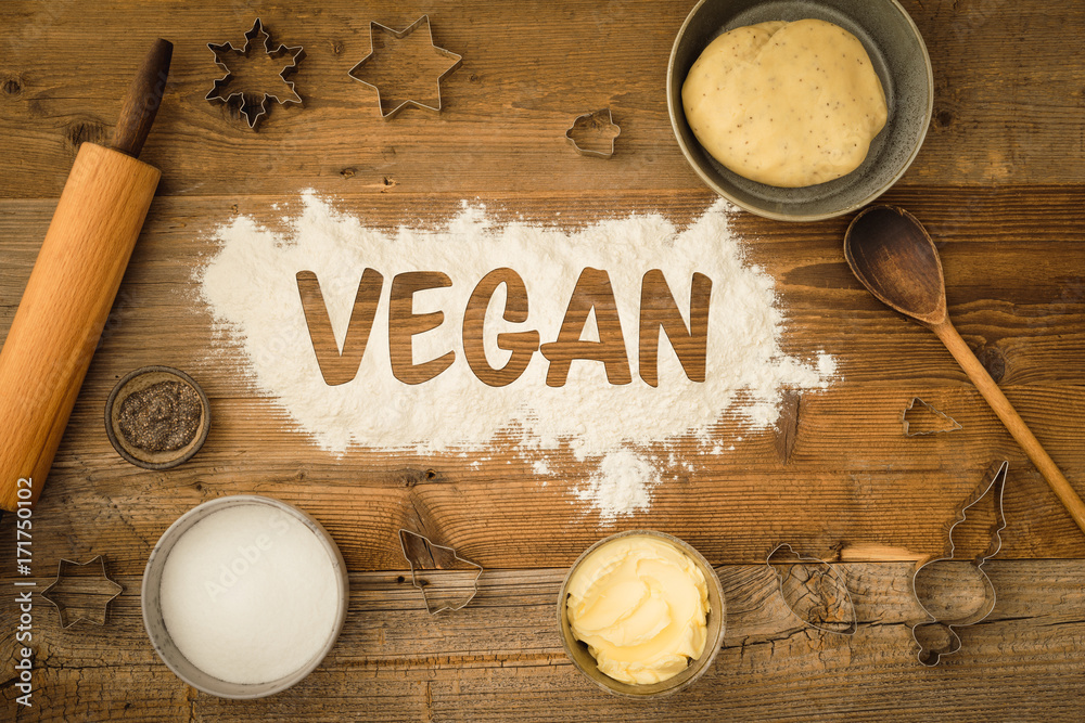 Φωτογραφία Flatlay collection of tools and ingredients for baking vegan Christmas cookies with margarine and chia seeds as egg replacement and the word vegan written in flour on a dark wooden table
