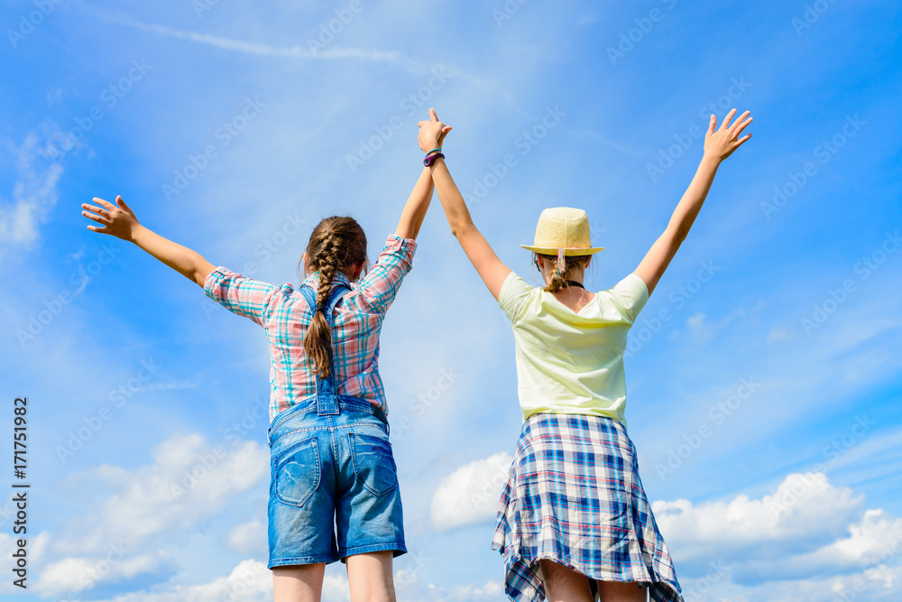 Happy friends with open arms under blue sky. Two girls having fun - relax outdoors. Friendship happiness summer holidays concept Happy friends with open arms under blue sky. Two girls having fun - relax outdoors. Friendship happiness summer holidays concept