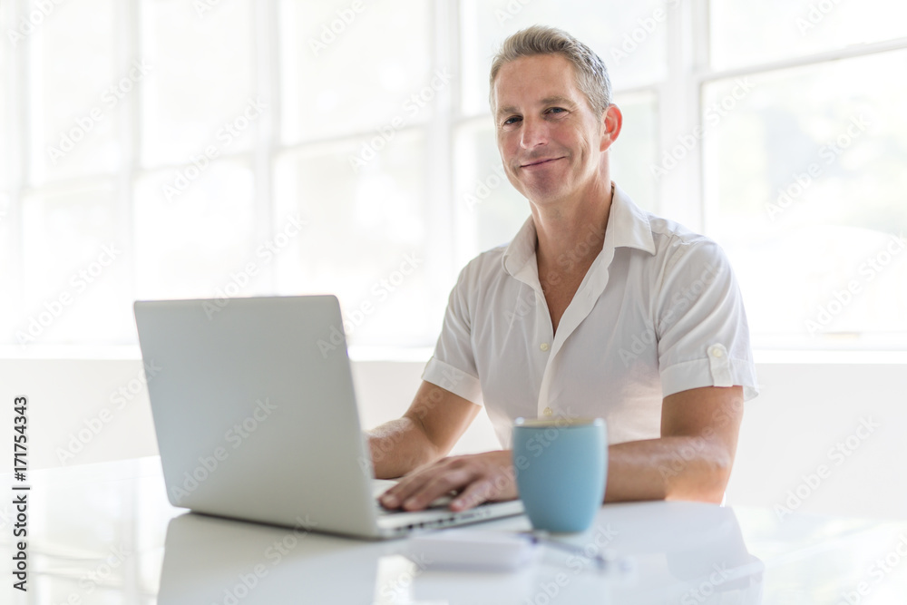 Mature Man Using Laptop On Desk At Home Mature Man Using Laptop On Desk At Home