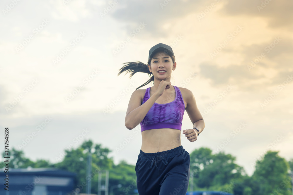Half Body Shot of a Pretty Athletic Woman Jogging at the Park  and Smiling at the Camera, with copy space