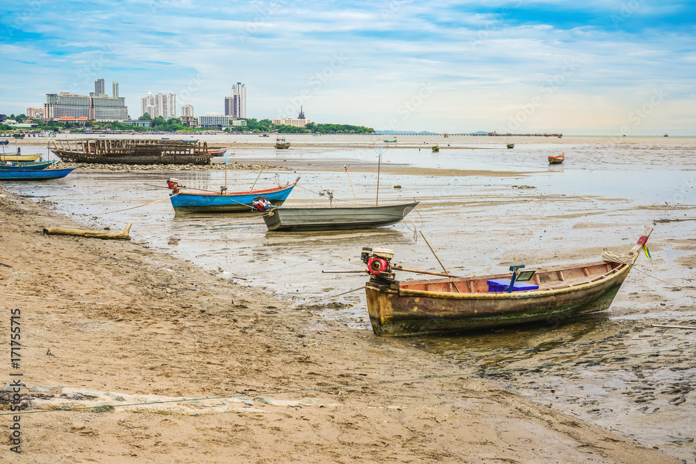 small fishing boat on beach with cityscape and bright sky background, Pattaya City, Thailand small fishing boat on beach with cityscape and bright sky background, Pattaya City, Thailand