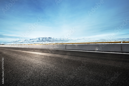 empty asphalt road with snow mountains in blue sky © zhu difeng
