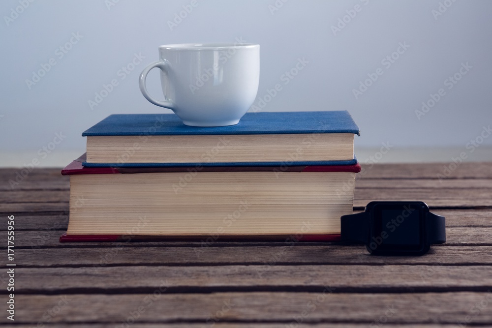 Naklejka premium Books with cup of coffee and smart watch on wooden table