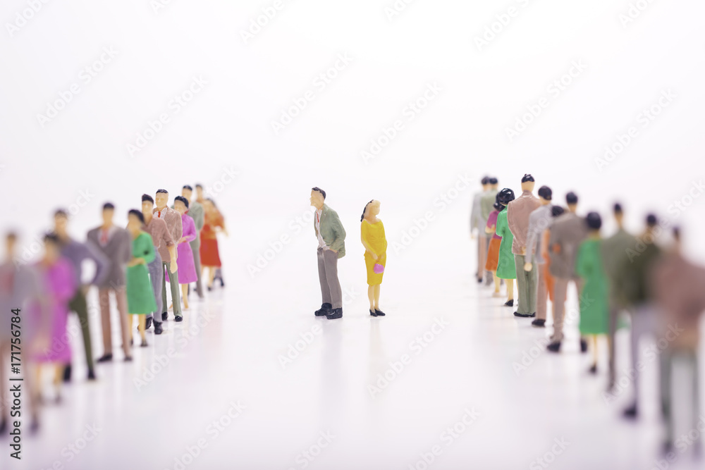 Miniature people in two lines across to each other with boss and woman in the middle over white background.