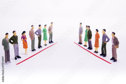 Miniature people in two lines across to each other over white background.
