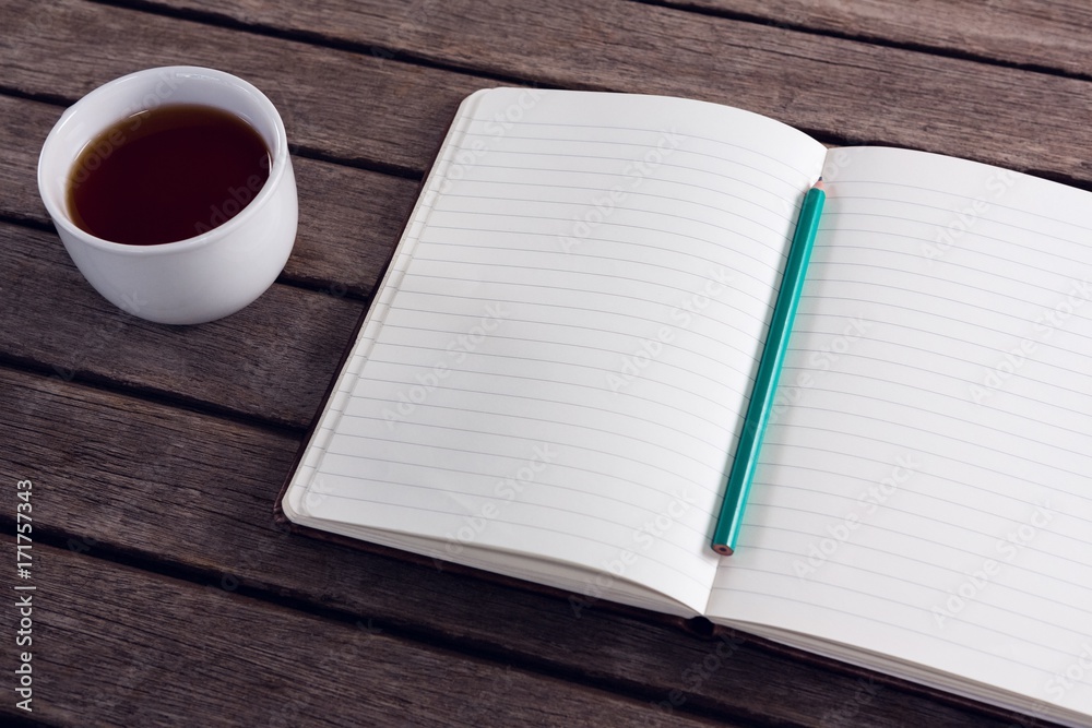 Close-up of pencil on open diary with cup of black coffee Close-up of pencil on open diary with cup of black coffee