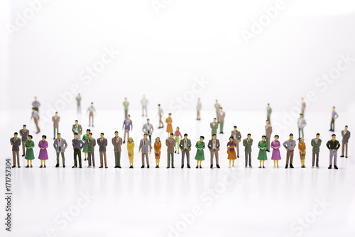 Group of miniature people over white background standing in line.