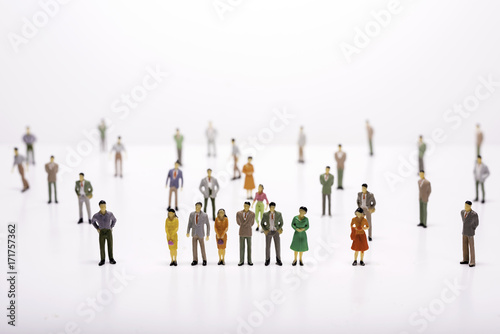 Group of miniature people over white background standing in line or circle.