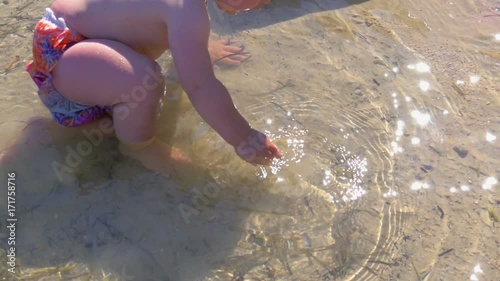 baby boy playing in shallow sea. crowling on sand. in slow-motion hd photo