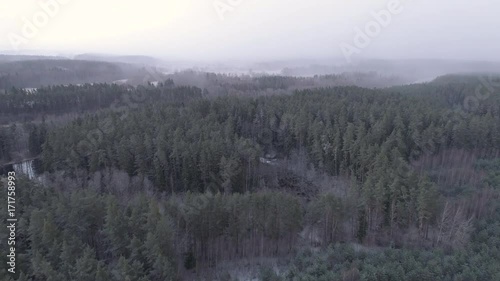 Aerial drone shot of forests and river during snow storm in Gauja National Park, Latvia photo