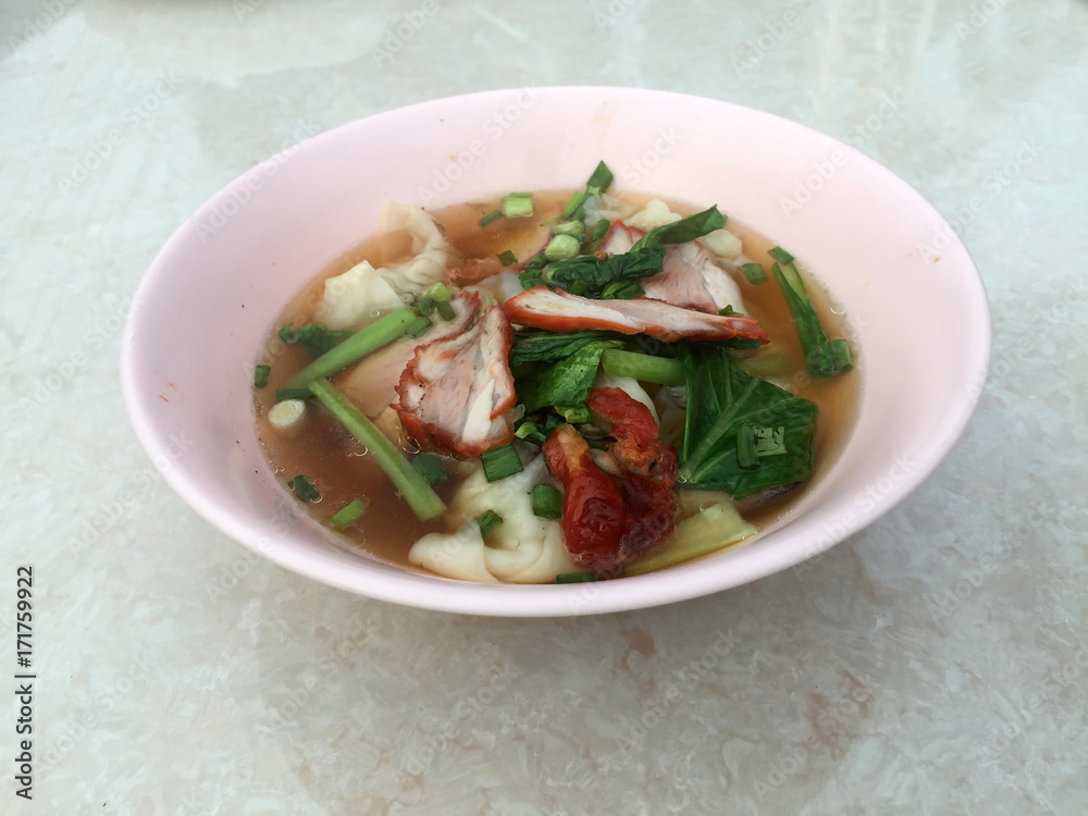 Wonton soup and Barbecued red pork with green Vegetable in the pink bowl on the white marble table. Wonton soup and Barbecued red pork with green Vegetable in the pink bowl on the white marble table.
