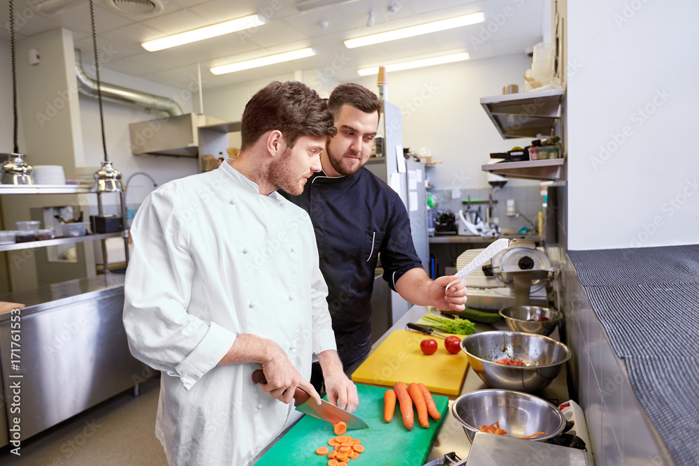 chef and cook cooking food at restaurant kitchen