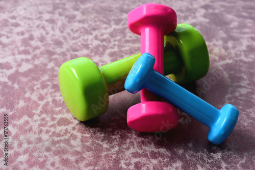 Barbells in green, pink and cyan color on wooden surface