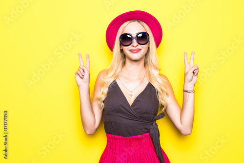 Shouting young woman in elegant striped dress winking and showing two finger or peace sign.