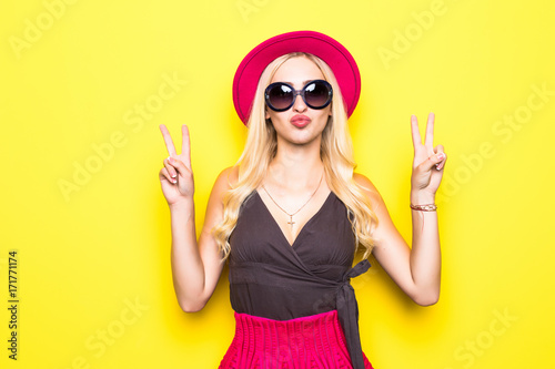 Shouting young woman in elegant striped dress winking and showing two finger or peace sign.