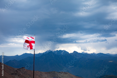 Georgia. Flag of Georgia against the background of mountains.