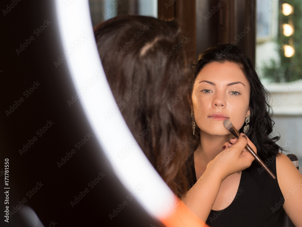 Portrait of make up artist applying cosmetics on young sexy woman's face. Oriental make up with long arrows and red shining lips. Trend 2018. Master Class Portrait of make up artist applying cosmetics on young sexy woman's face. Oriental make up with long arrows and red shining lips. Trend 2018. Master Class