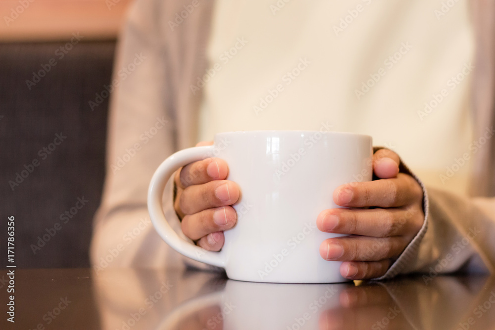 Person hand holding a white cup of coffee with blurry background Person hand holding a white cup of coffee with blurry background