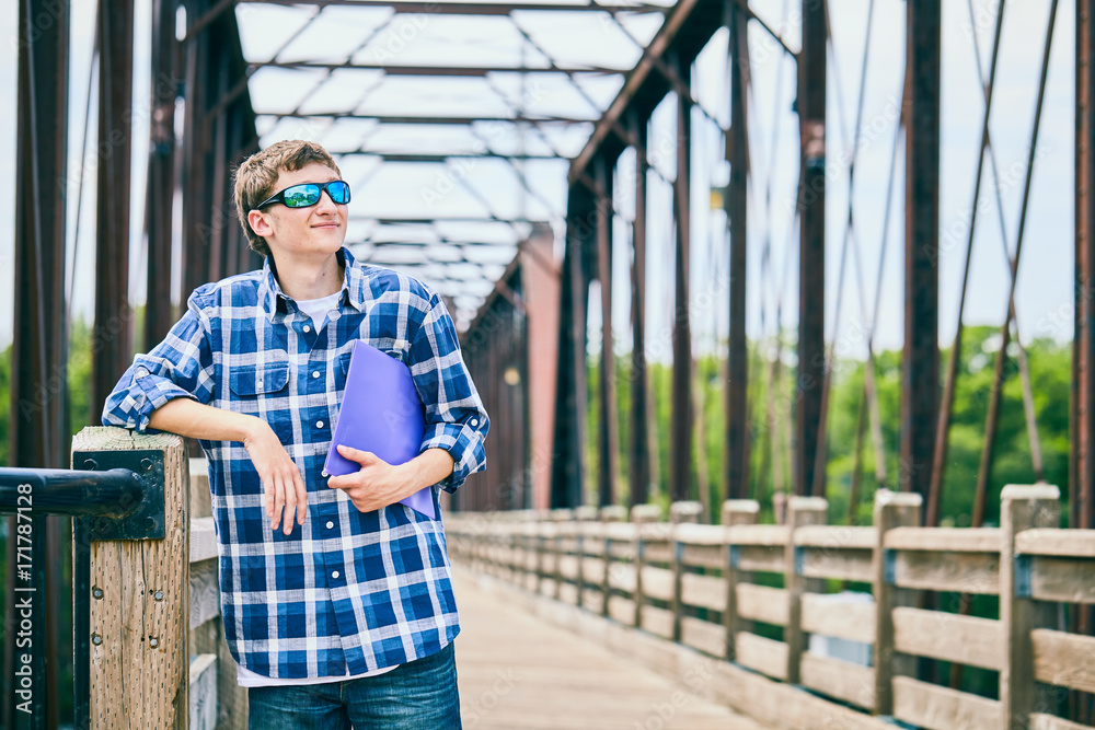 Smiling young guy in sunglasses holding folder Smiling young guy in sunglasses holding folder