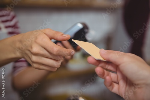 Cropped hand of customer making payment to owner