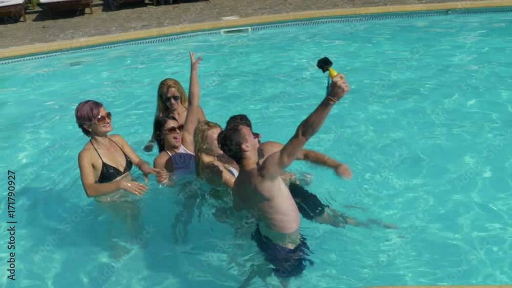 Group of friends taking selfie in the pool water at the villa Group of friends taking selfie in the pool water at the villa