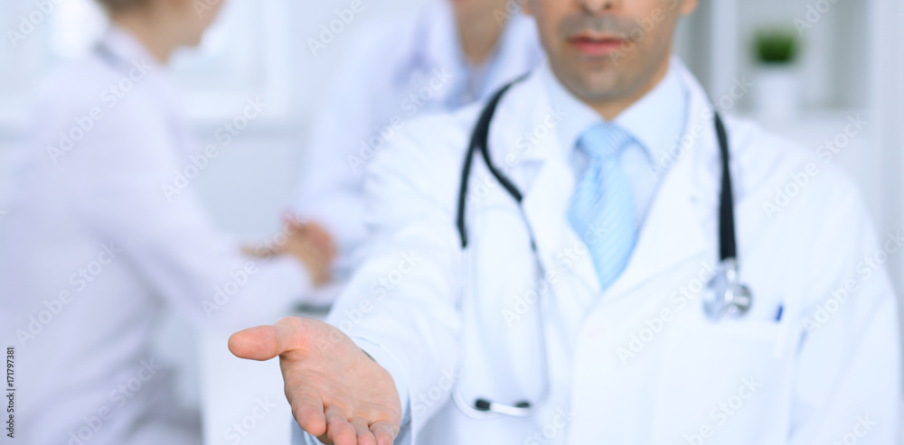 Male medicine doctor offering helping hand  for  handshake. Partnership and trust concept. 