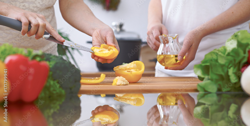 Close-up of four human hands are cooking in a kitchen. Friends having fun while preparing fresh salad. Vegetarian, healthy meal and friendship concept Close-up of four human hands are cooking in a kitchen. Friends having fun while preparing fresh salad. Vegetarian, healthy meal and friendship concept