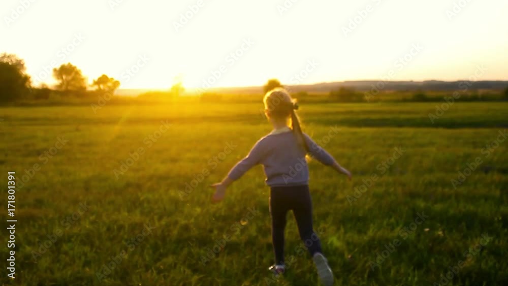 Happy young girl running on feather grass field in sunset light. Nature lifestyle and amazing view around. Happy young girl running on feather grass field in sunset light. Nature lifestyle and amazing view around.