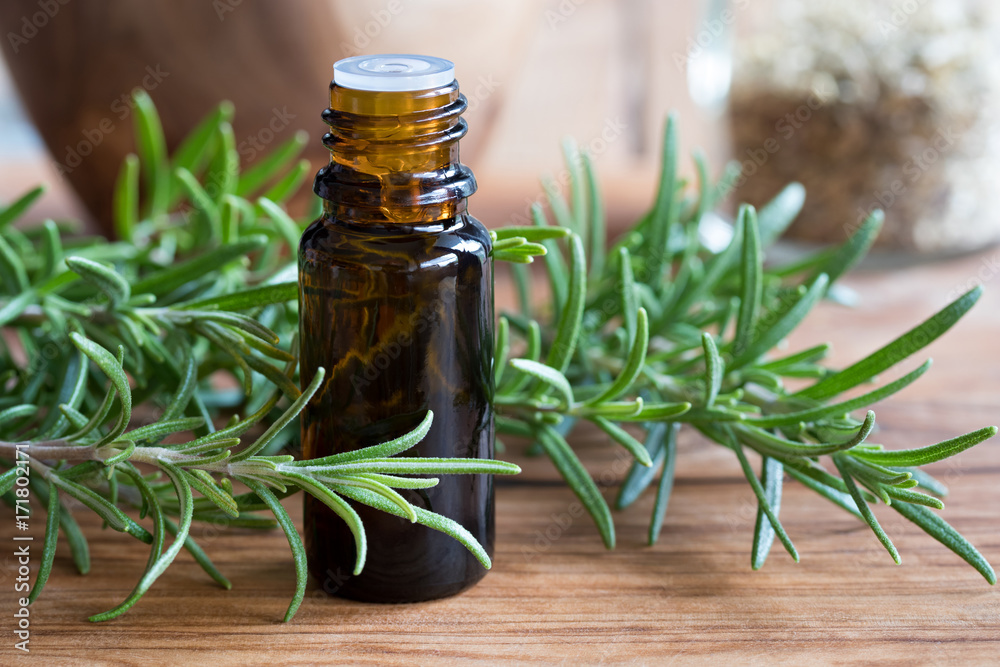 A bottle of rosemary essential oil with fresh rosemary A bottle of rosemary essential oil with fresh rosemary