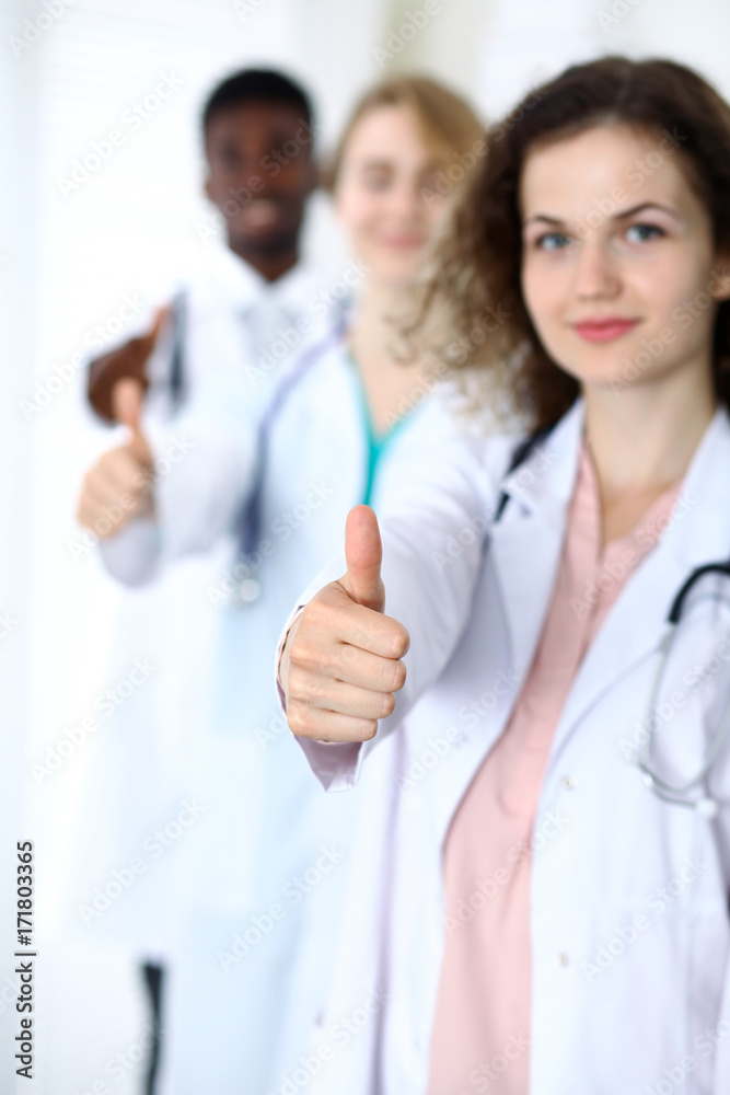 Group of doctors showing OK or approval sign with thumb up. High level and quality medical service, best treatment and patient care concept Group of doctors showing OK or approval sign with thumb up. High level and quality medical service, best treatment and patient care concept