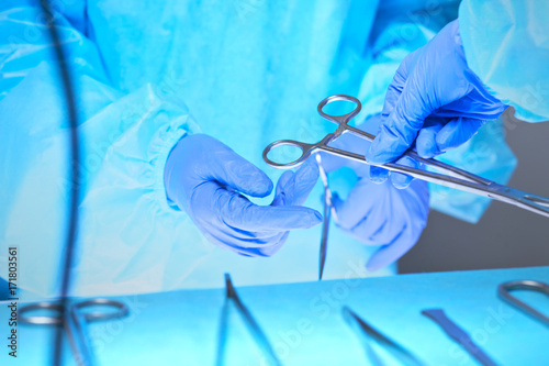 Close-up of of surgeons hands at work in operating theater toned in blue