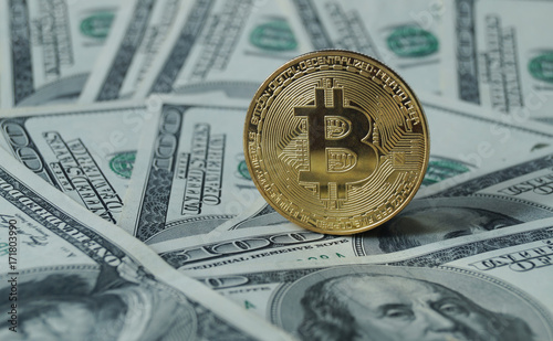 Obraz na płótnie A symbolic coins of bitcoin on banknotes of one hundred dollars. w salonie