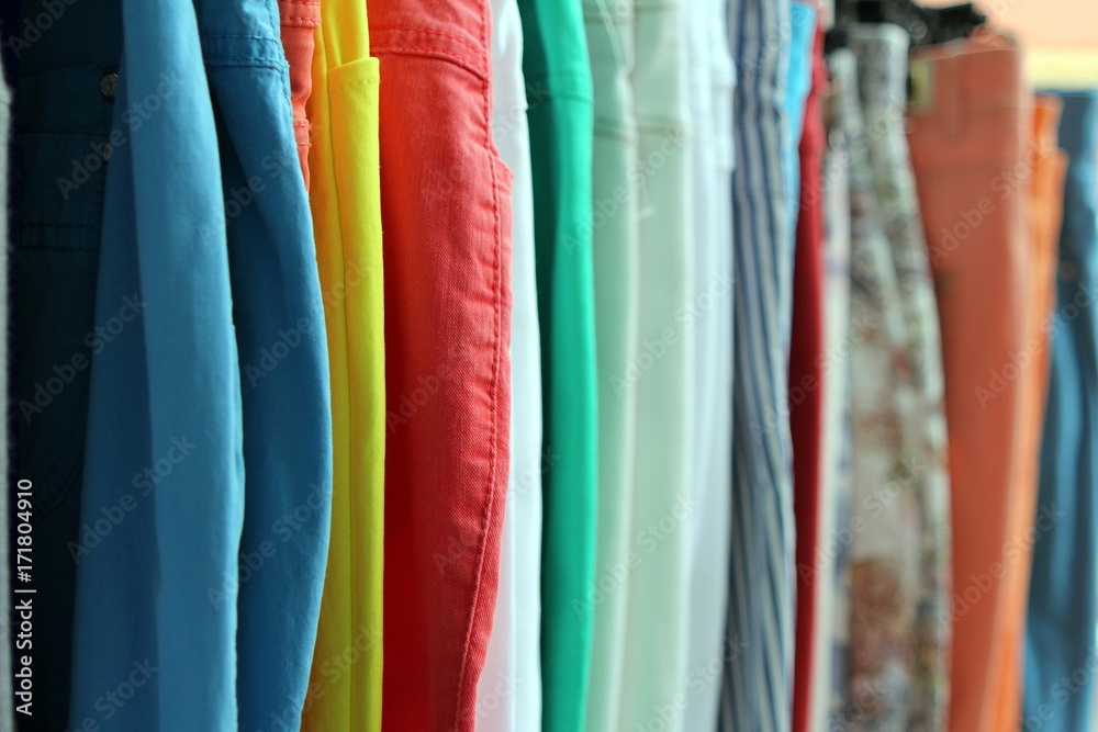 Shallow focus shot of colorful trousers and jeans on a shop rail