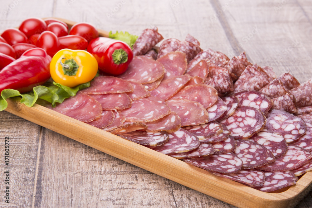 Set of meat delicatessen, tomatoes and peppers on a wooden table.