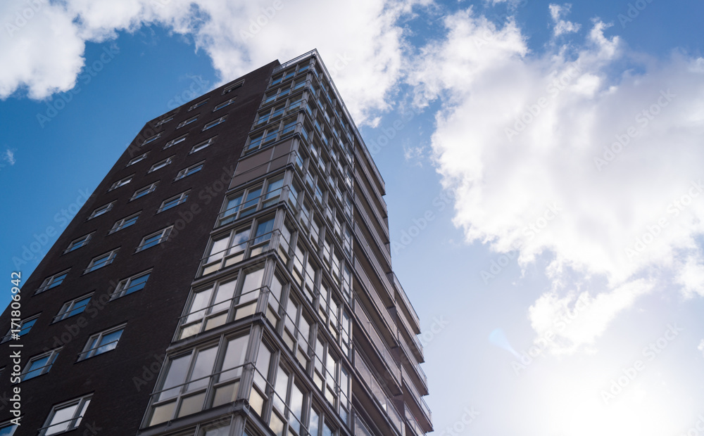 a high skyscraper in sunlight with white clouds and a blue sky as background a high skyscraper in sunlight with white clouds and a blue sky as background