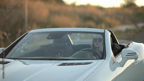 beautiful sexy girl with long hair in a leather jacket and leather pants in sunglasses sits in a cabriolet photo