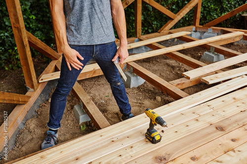 man drilling and measuring wood for deck