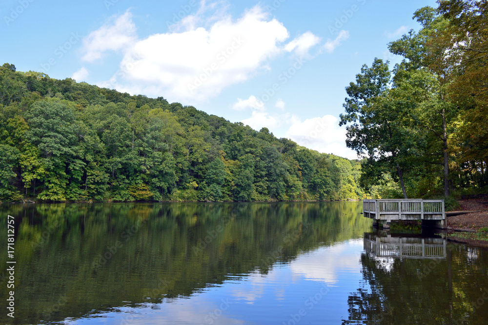 Scenic landscape view of a smooth lake reflecting the trees of the forest Scenic landscape view of a smooth lake reflecting the trees of the forest