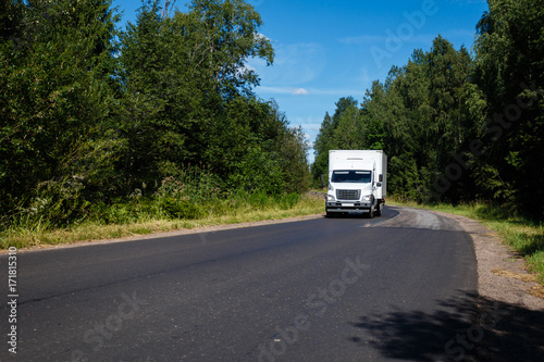 White van on the asphalt road. The truck delivers cargo on the highway.