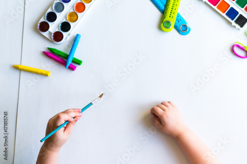 The child holds the brush over the sheet